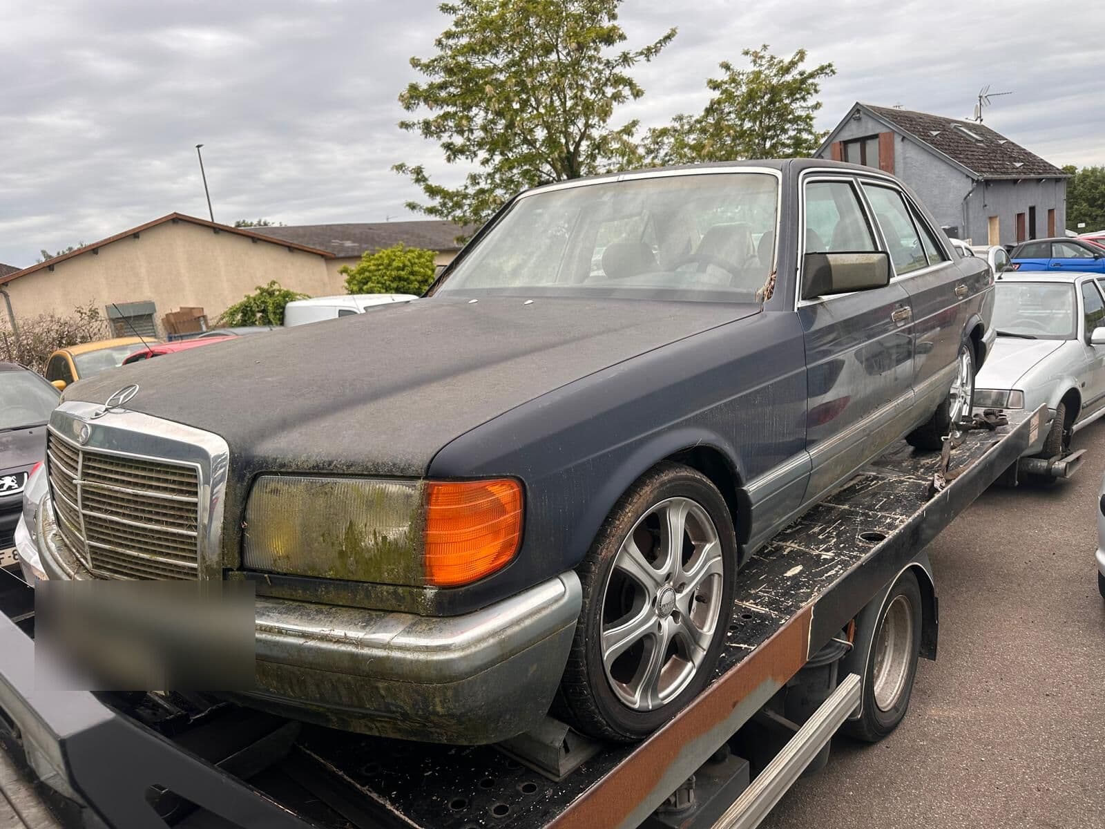 Berline Mercedes hors d'usage chargée sur la dépanneuse plateau