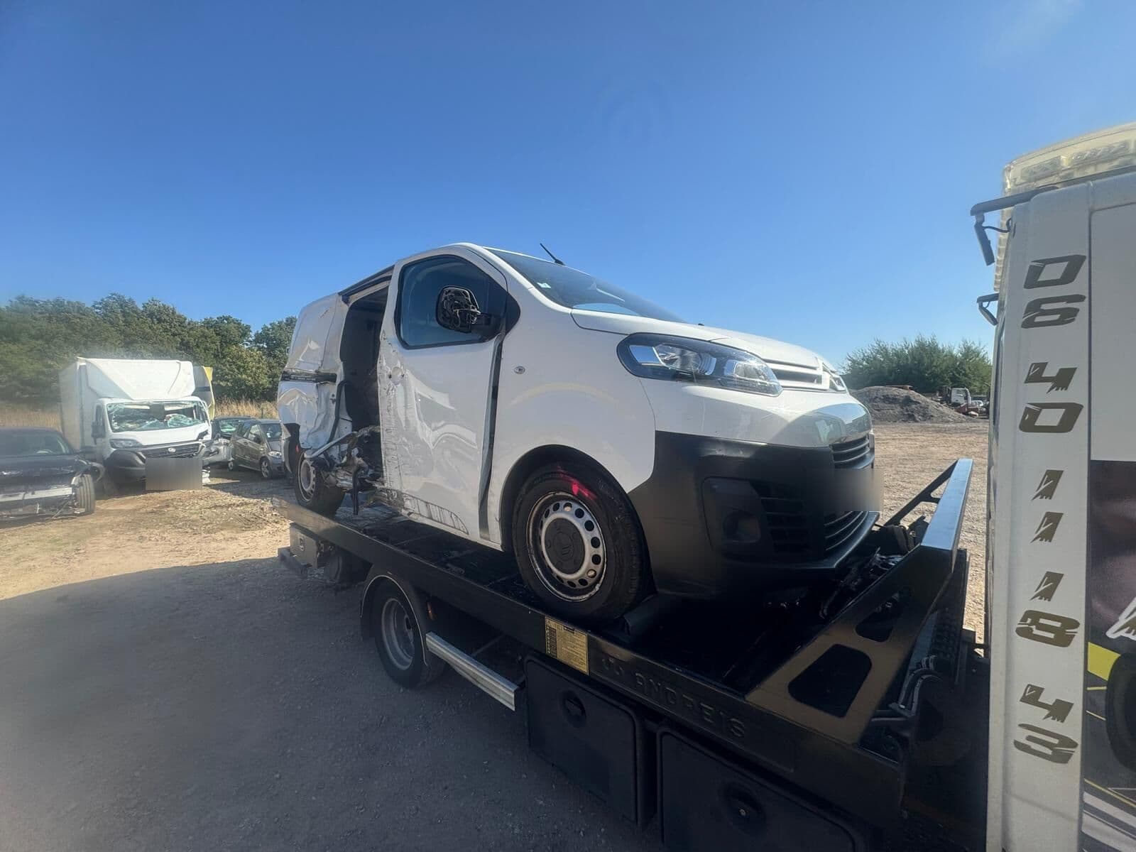 Utilitaire blanc accidenté arrimé sur le plateau de la dépanneuse